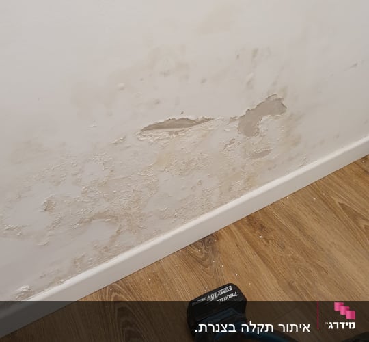 קיר עם רטיבות וכלי עבודה על הרצפה
